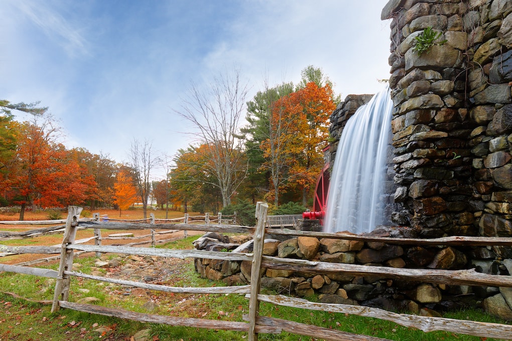 Longfellow's Wayside Inn Grist Mill with water wheel and cascade water fall in Autumn at sunrise, history of Sudbury Massachusetts USA